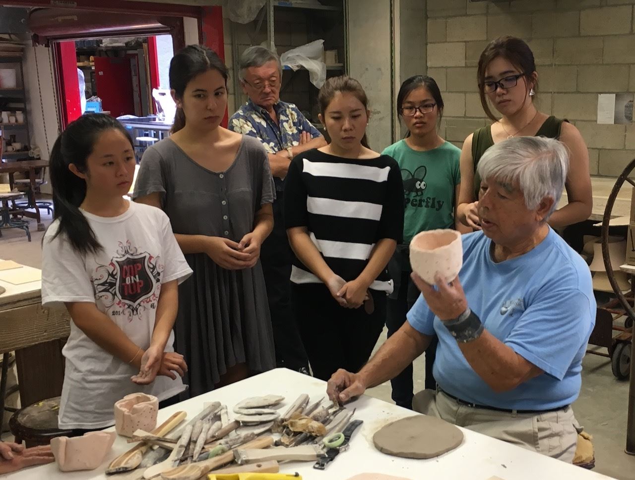 Previous Tea Bowl Workshop attendees learning about the importance of crafting a tea bowl.
