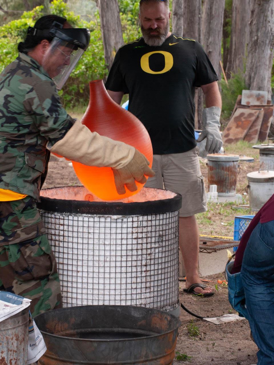 Participants removing ceramic pot from Raku kiln